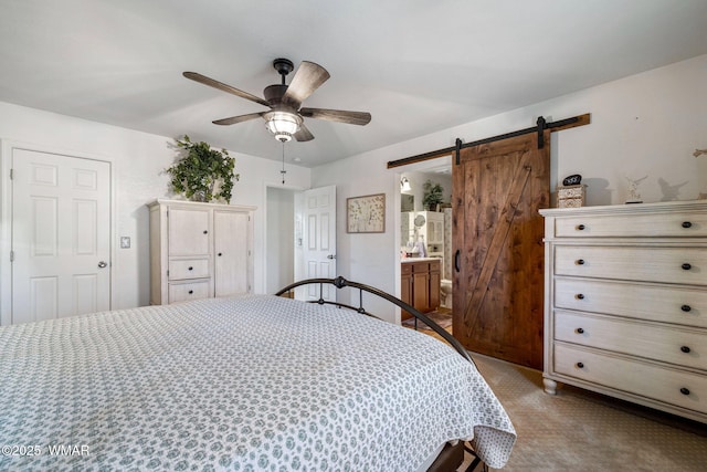 bedroom with ceiling fan, a barn door, ensuite bath, and light colored carpet