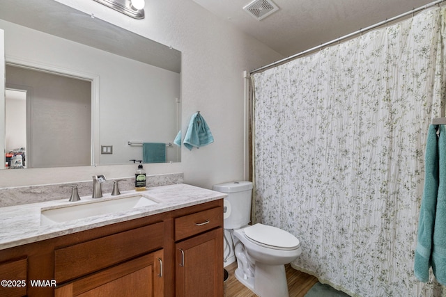 bathroom with visible vents, vanity, toilet, and wood finished floors