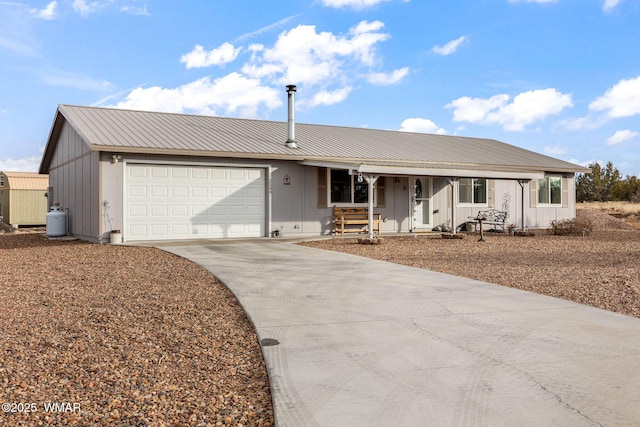 single story home featuring concrete driveway, metal roof, an attached garage, covered porch, and board and batten siding