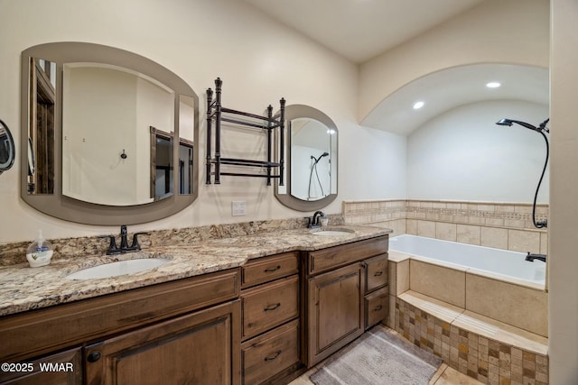 bathroom with tiled tub, a sink, and double vanity