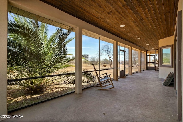 unfurnished sunroom with wood ceiling and finished concrete floors