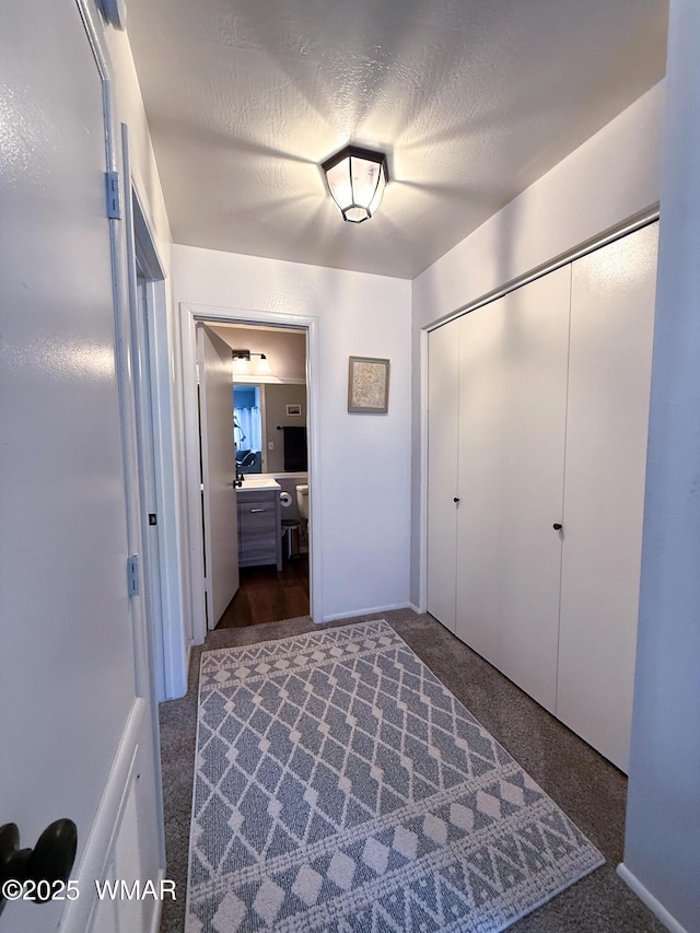 unfurnished bedroom featuring a textured ceiling, dark colored carpet, and a closet