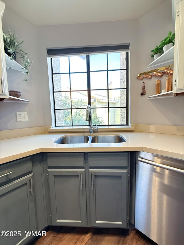 kitchen featuring a sink, open shelves, stainless steel dishwasher, and light countertops