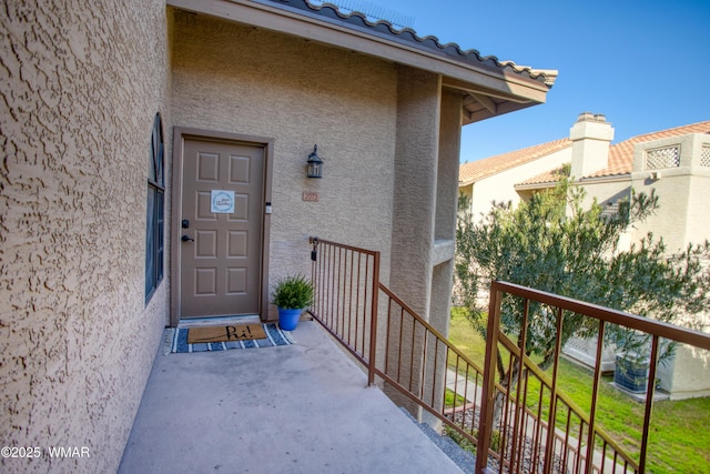 view of exterior entry with a tiled roof and stucco siding