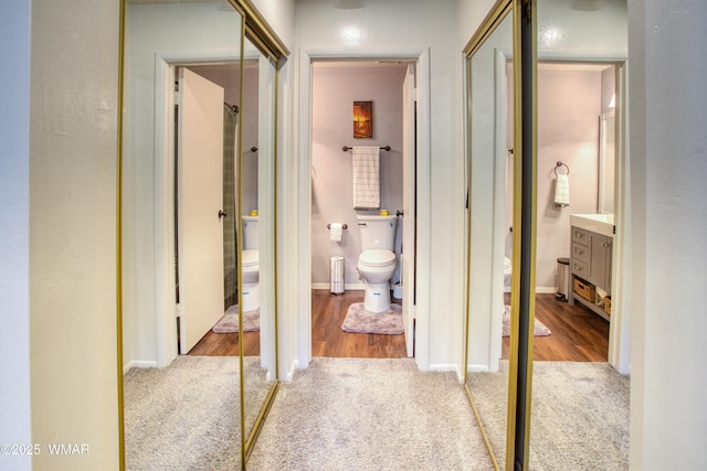 hallway with light wood-style flooring, baseboards, and light colored carpet