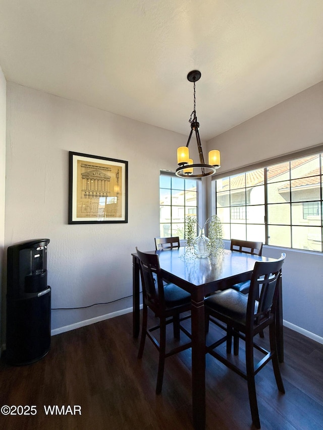 dining room featuring dark wood-type flooring, a notable chandelier, and baseboards