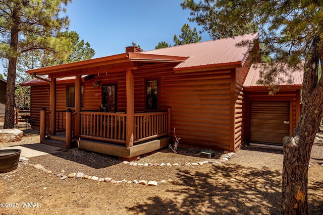1761 N Bison Ct, Show Low, AZ 85901 - view of front of home featuring covered porch, a chimney, a metal roof, faux log siding, and a garage