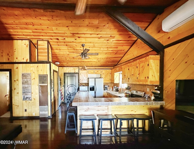 3403 Top View Rd, Overgaard, AZ 85933 - kitchen with tile countertops, stainless steel refrigerator with ice dispenser, a wall unit AC, a peninsula, and wood walls