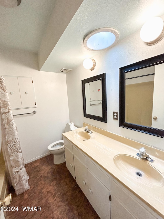 full bathroom with double vanity, a textured ceiling, visible vents, and a sink