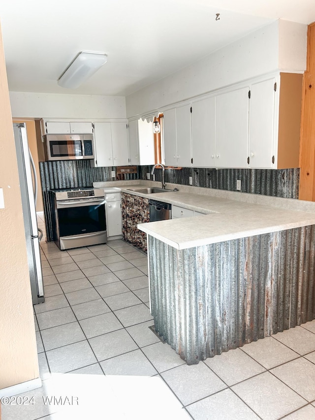 kitchen featuring light tile patterned floors, stainless steel appliances, a sink, white cabinets, and light countertops