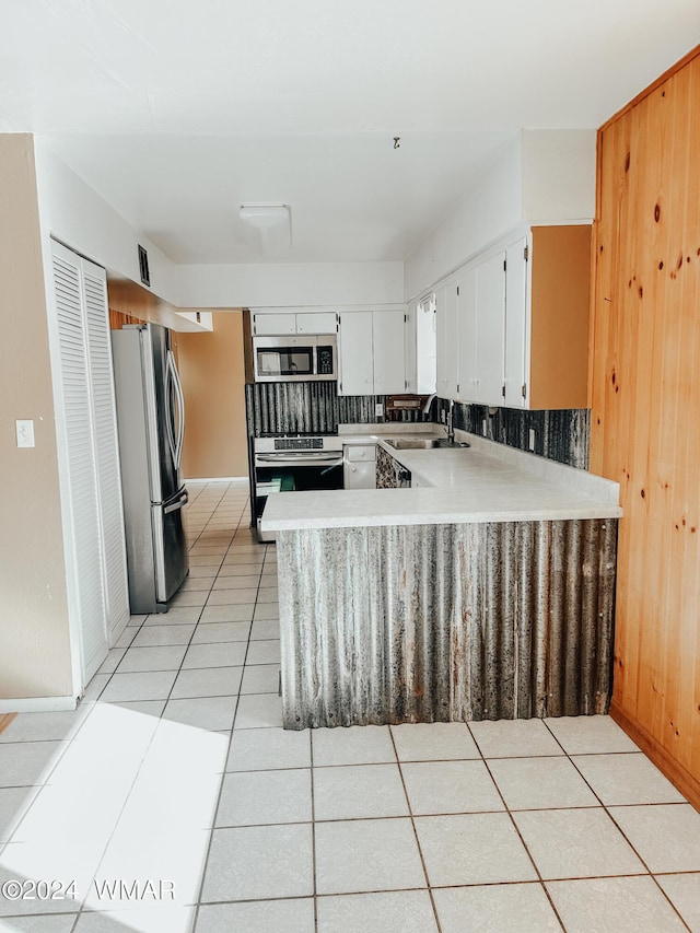 kitchen featuring light tile patterned floors, stainless steel appliances, light countertops, white cabinets, and a sink