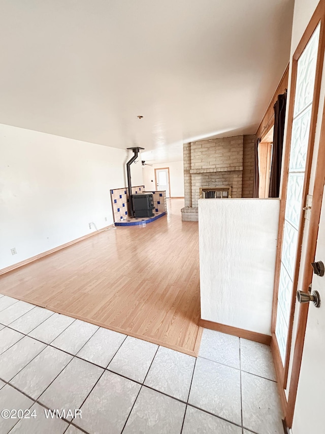 unfurnished living room with a healthy amount of sunlight, a brick fireplace, baseboards, and tile patterned floors