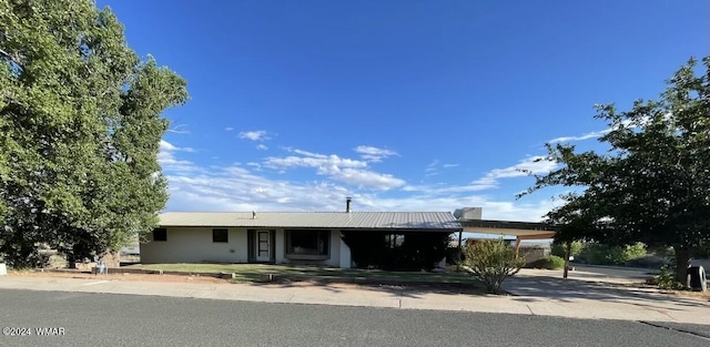 ranch-style home featuring driveway, metal roof, and a carport