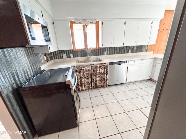 kitchen featuring light tile patterned floors, stainless steel appliances, a sink, white cabinets, and light countertops