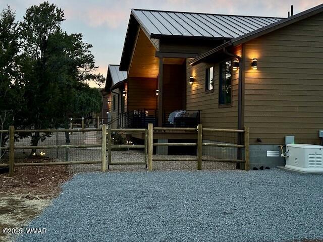 2344 Hellcat Cir, Overgaard, AZ 85933 - view of home's exterior featuring a standing seam roof, a metal roof, and a gate