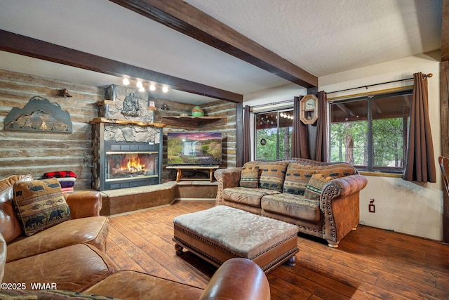 2444 S Jan Ln, Pinetop, AZ 85935 - living room featuring beamed ceiling, hardwood / wood-style flooring, a stone fireplace, and a textured ceiling
