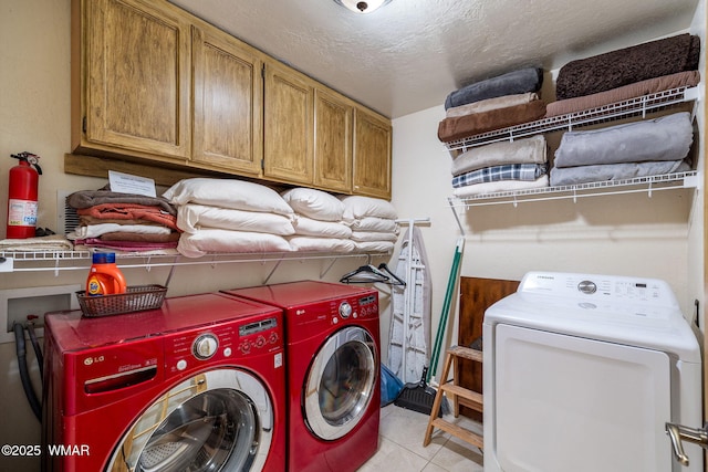 2444 S Jan Ln, Pinetop, AZ 85935 - laundry area featuring separate washer and dryer, cabinet space, light tile patterned floors, and a textured ceiling