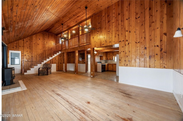 3510 Sunset Ln, Lakeside, AZ 85929 - unfurnished living room with stairway, ceiling fan, wood walls, wood-type flooring, and a wood stove