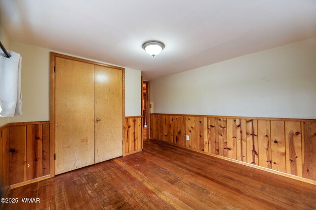 3510 Sunset Ln, Lakeside, AZ 85929 - unfurnished bedroom featuring hardwood / wood-style floors, a wainscoted wall, wood walls, and a closet