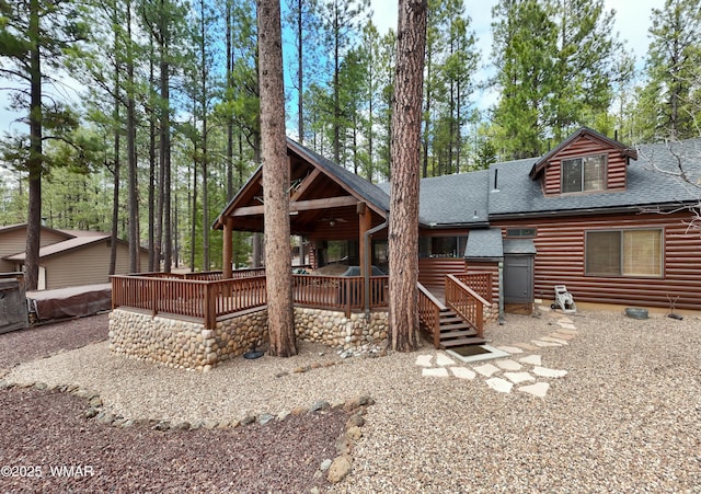 rear view of house featuring a shingled roof, a deck, and log veneer siding