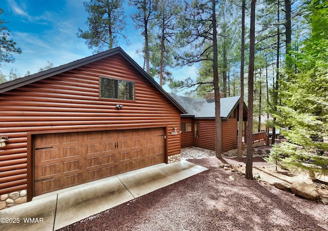 view of property exterior featuring a garage, faux log siding, and dirt driveway