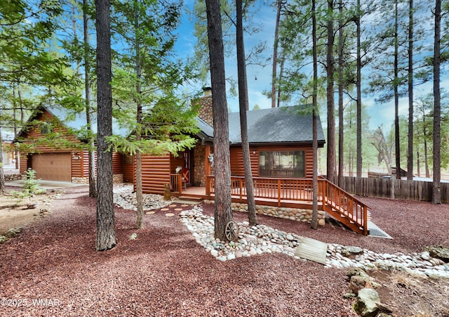 log cabin with a garage, a deck, fence, and faux log siding
