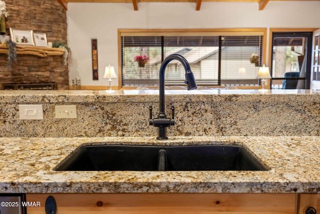 details featuring a sink and light stone countertops