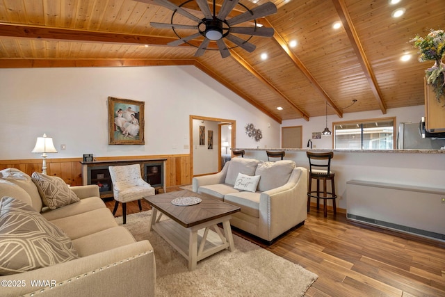 living room featuring a wainscoted wall, light wood finished floors, beam ceiling, and wood ceiling