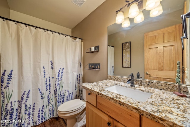 bathroom featuring toilet, vanity, and visible vents