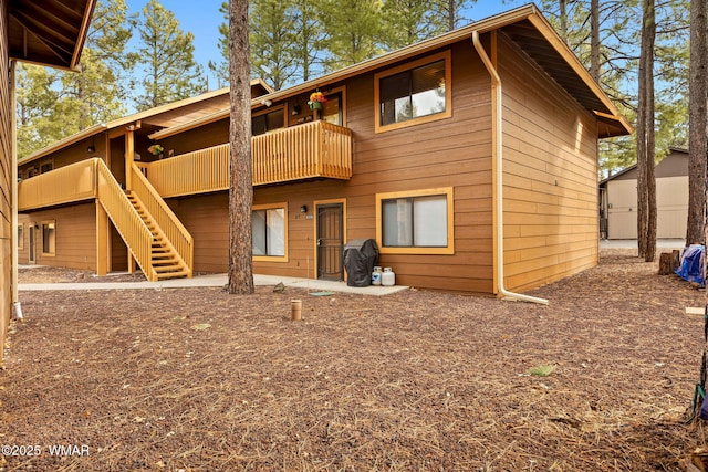 back of house featuring a balcony and stairs