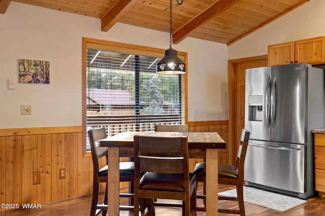 dining space featuring wooden walls, wooden ceiling, wainscoting, and lofted ceiling with beams