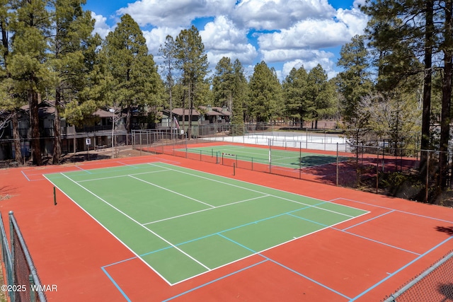 view of tennis court featuring community basketball court and fence