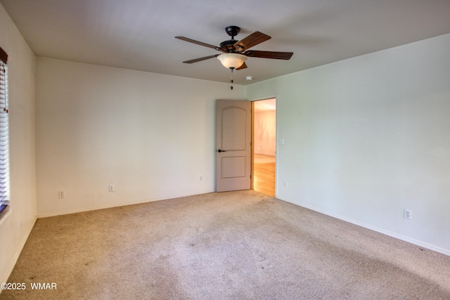 empty room featuring a ceiling fan and carpet