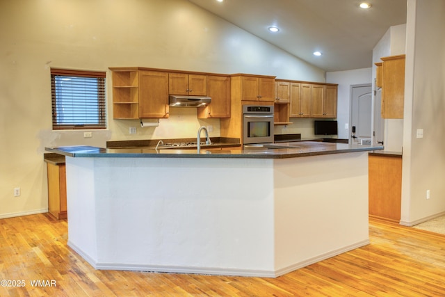 kitchen with brown cabinets, open shelves, light wood-type flooring, oven, and under cabinet range hood