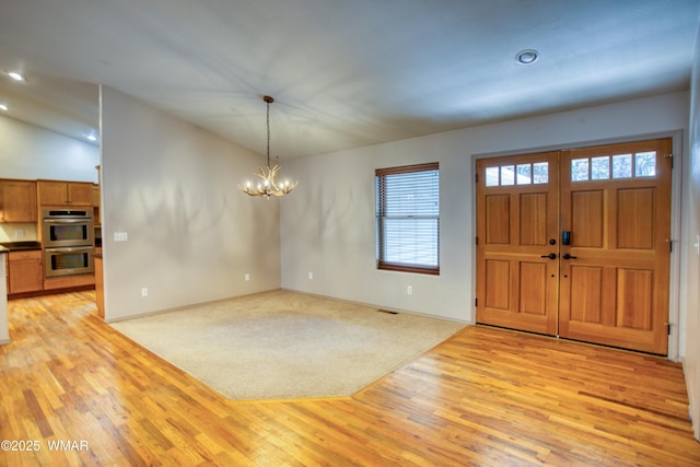 foyer entrance featuring a chandelier, recessed lighting, vaulted ceiling, and light wood-style flooring