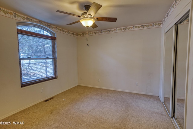 unfurnished bedroom featuring light carpet, multiple windows, visible vents, and a closet