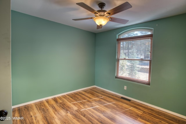 unfurnished room featuring ceiling fan, wood finished floors, visible vents, and baseboards