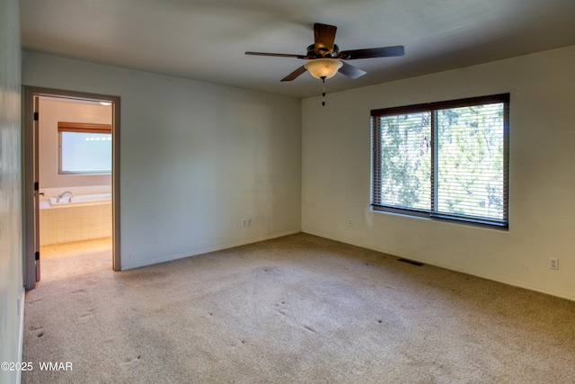 carpeted empty room featuring visible vents and a ceiling fan