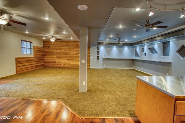 below grade area with wood walls, wood finished floors, and a ceiling fan