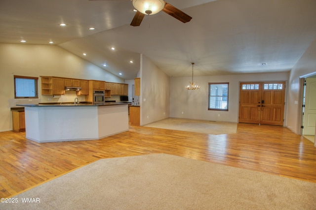 kitchen with stainless steel oven, light wood-style floors, open floor plan, open shelves, and dark countertops