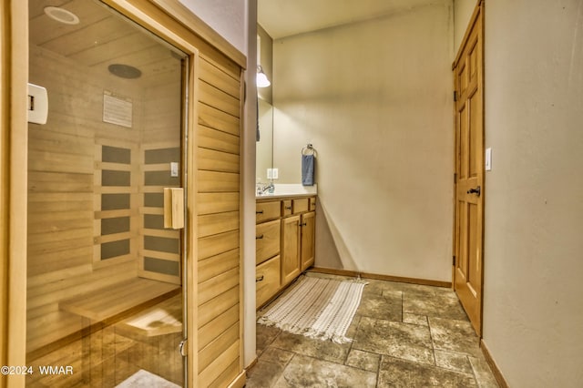 bathroom featuring a sauna, vanity, stone tile flooring, and baseboards