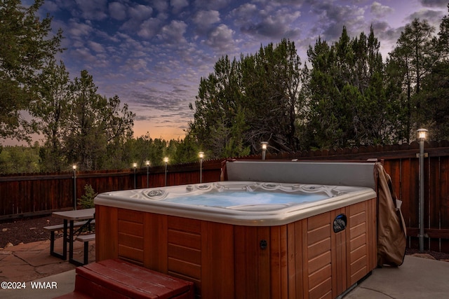 patio terrace at dusk with a fenced backyard and a hot tub