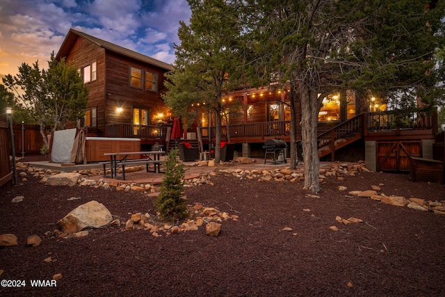 rear view of property with a patio area, a hot tub, a wooden deck, and stairs
