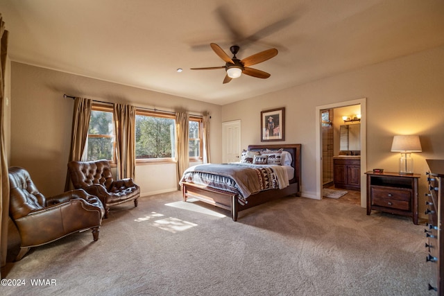 bedroom with light colored carpet, ceiling fan, baseboards, and ensuite bathroom