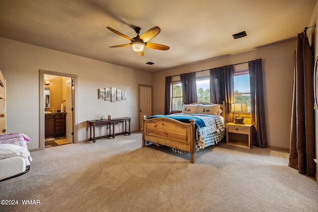 bedroom with baseboards, visible vents, connected bathroom, light colored carpet, and ceiling fan