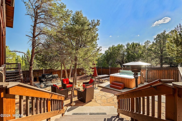 wooden terrace featuring a patio area, a hot tub, an outdoor hangout area, and a fenced backyard