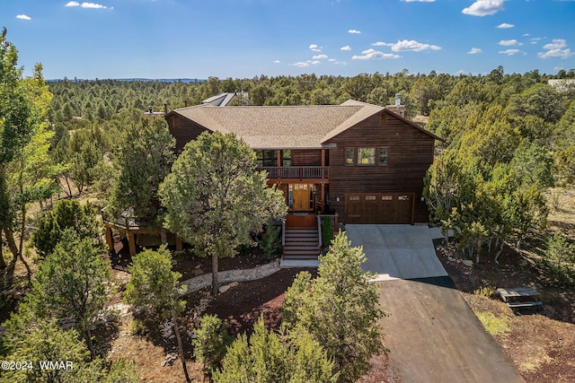 rustic home with driveway, an attached garage, stairway, and a view of trees