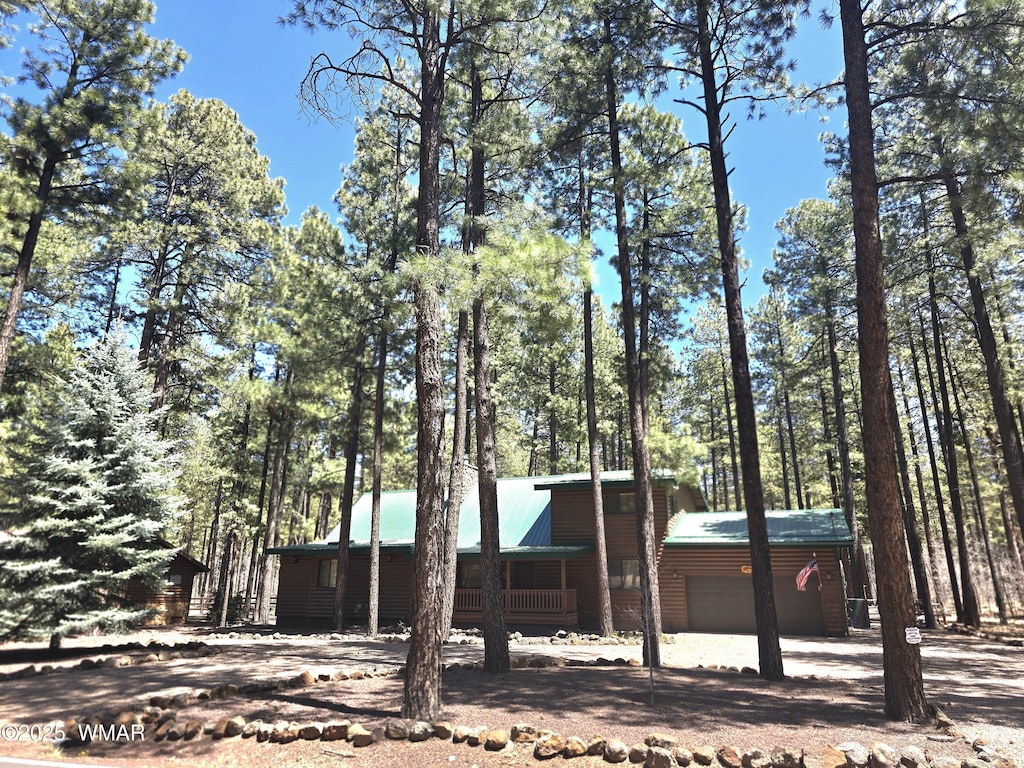 view of front facade featuring metal roof, faux log siding, and an attached garage