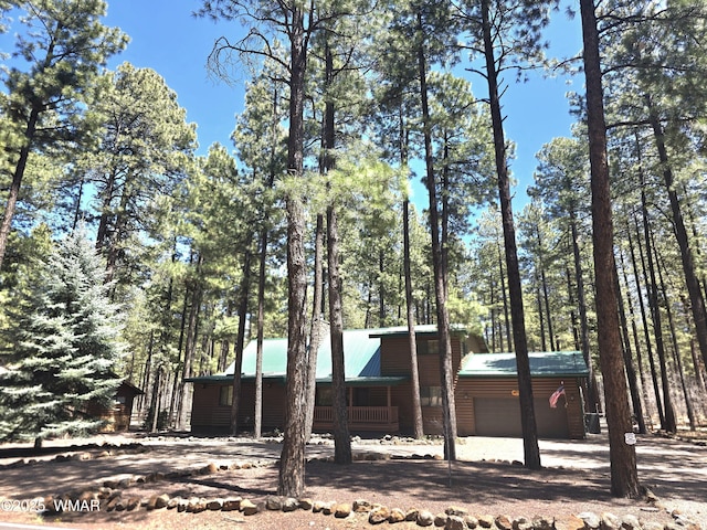 view of front facade featuring metal roof, faux log siding, and an attached garage