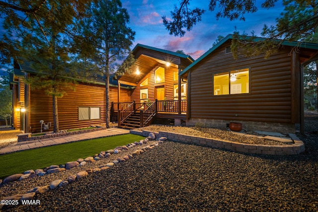 view of front of house featuring faux log siding, a front yard, and covered porch